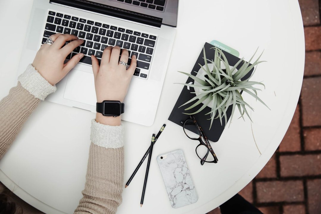 Tangan mengetik di laptop di meja putih