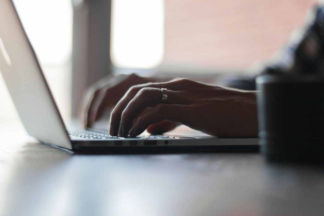 Tangan mengetik di laptop dekat jendela