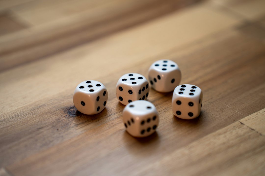 Five white dice with black pips scattered on a wooden surface