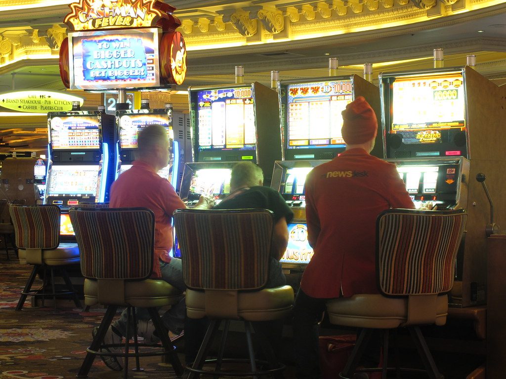 Pengunjung duduk di depan mesin slot kasino